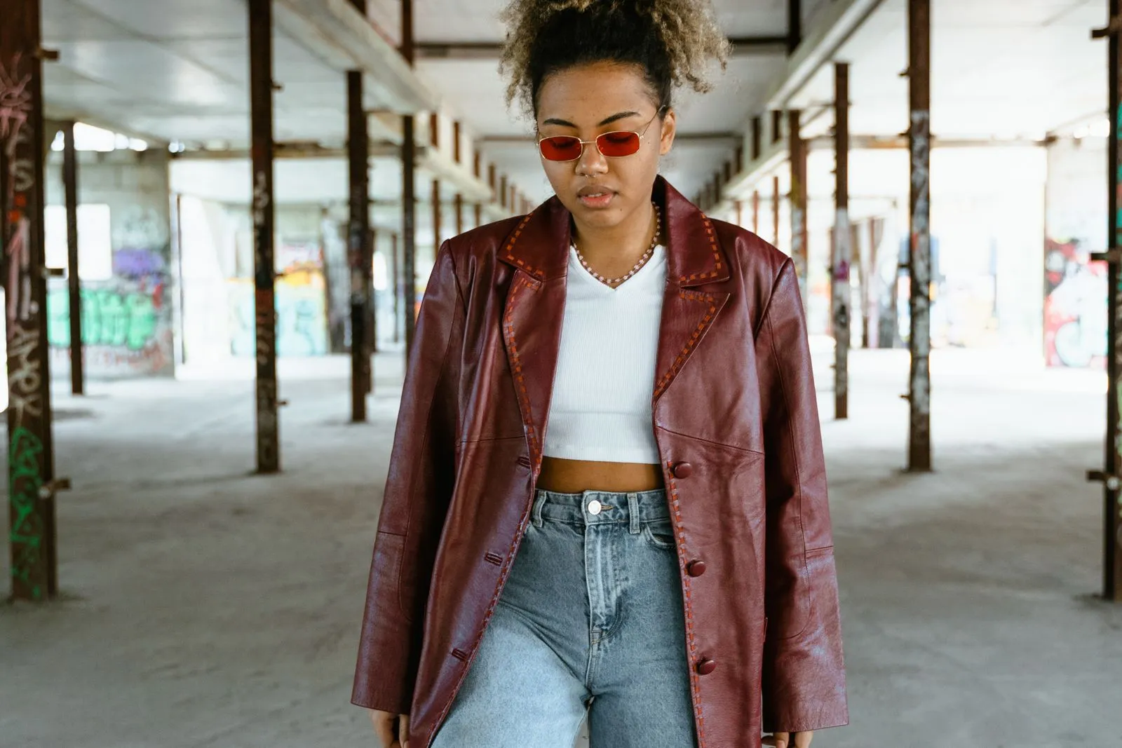 Fashionable woman with a bold look stands confidently in a graffiti-covered urban background.